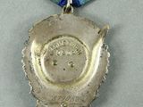 silver medal with a blue ribbon around it on a gray surface