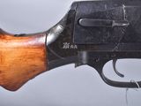 a close up of a gun with a wooden handle on a gray background