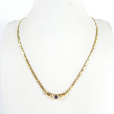 un collier en or orné d'une pierre bleue autour du cou d'un mannequin