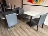 a table and chairs in a room with a painting on the wall