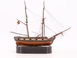 une maquette de bateau posée sur un socle, sur une surface blanche