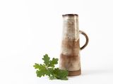 a brown vase with a plant in it on a white surface