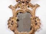 un miroir ancien doré orné d'un motif décoratif, accroché au mur