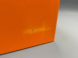 une boîte orange posée sur une table blanche, près d'un mur gris