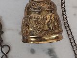 a brass bell hanging on a chain on a marble surface