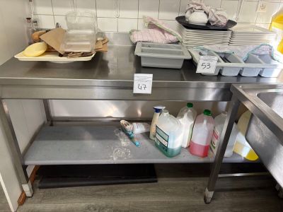 une table de travail en acier inoxydable sur laquelle se trouvent de nombreux produits d'entretien