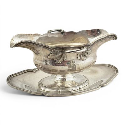 une saucière ancienne en argent posée sur un plateau, sur une surface blanche