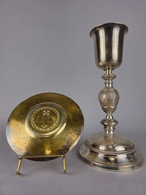 assiette en argent et tasse en argent posées sur un support, sur fond gris