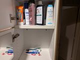 une armoire blanche sur laquelle sont posés de nombreux produits d'entretien