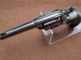 a silver revolver on a clear stand on a brown surface