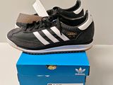 une paire de chaussures noires et blanches posée sur une boîte bleue