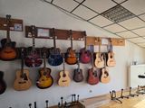 many guitars hanging on the wall in this room