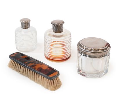 trois bouteilles et un pinceau posés sur une surface blanche