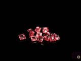 some pink diamonds on a black surface with a black background