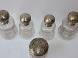 four small glass bottles with silver lids and a silver lid