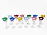a lot of different colored wine glasses on a white surface