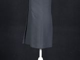 a black dress on a mannequin stand against a black background