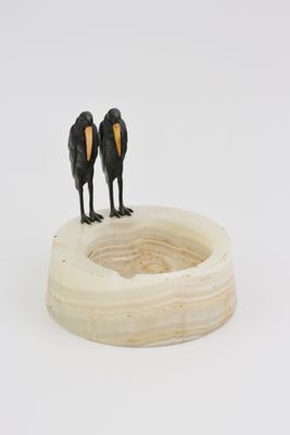 two birds that are standing on top of a bowl