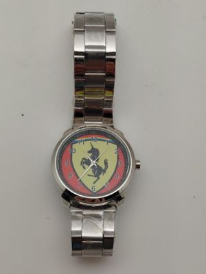 montre en argent avec un logo Ferrari rouge et jaune sur le cadran