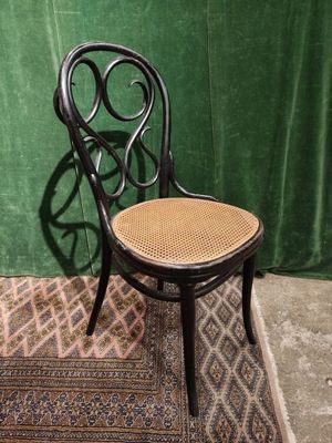 a black chair with a wicker seat on a rug