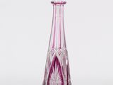 vase en verre violet et transparent, au sommet pointu, posé sur une surface blanche