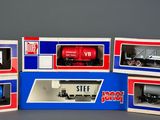 several model train cars in boxes on a gray surface