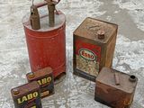 three old oil cans sitting next to each other on the ground