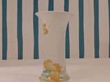a white vase sitting on a table with a blue and white striped wall behind it
