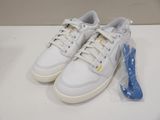 pair of white sneakers with yellow and blue laces on a white surface