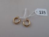 deux paires de boucles d'oreilles créoles en or avec une étiquette de prix sur fond blanc