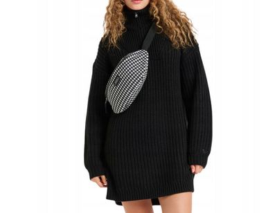 une femme vêtue d'une robe-pull noire et portant un sac banane