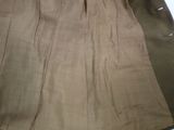 beige pleated skirt on a bed with a white sheet on the floor