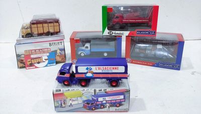 quatre camions miniatures posés sur une surface blanche