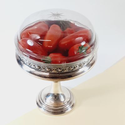 a glass bowl filled with tomatoes on top of a table