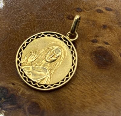 a gold pendant with a picture of the virgin mary and child