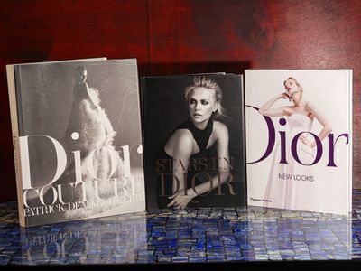 Trois livres sont posés sur une table dont le sol est recouvert de carreaux bleus.
