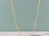 un gros plan d'un collier de perles dorées posé sur une surface en marbre