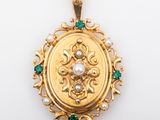 a close up of a gold locke with emeralds and pearls