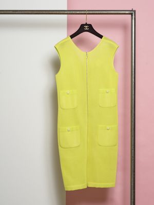une robe jaune suspendue à un portemanteau devant un mur rose