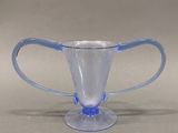 un verre bleu avec une anse posé sur une table