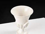 a white vase sitting on a table with a black background