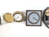 four different clocks sitting next to each other on a white surface