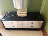 a black and white dresser with a lamp on top of it