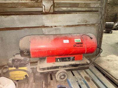 un réservoir rouge posé sur une palette dans un garage