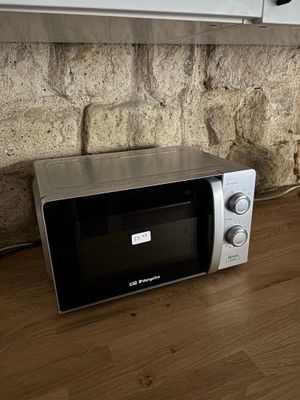 un micro-ondes posé par terre près d'une fenêtre