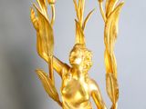 a gold statue of a woman holding a bouquet of flowers