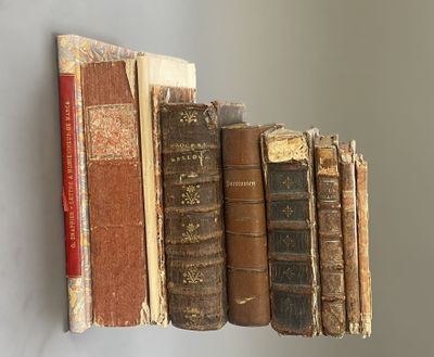 several old books are lined up on a shelf on a wall