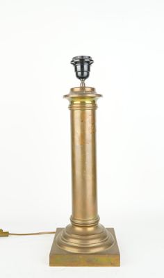 une lampe de table en laiton vieilli surmontée d'un abat-jour noir