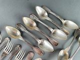 a lot of silver spoons and forks on the table