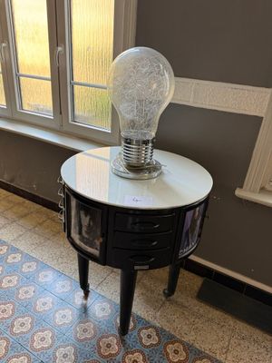 une table sur laquelle est posée une lampe, devant une fenêtre